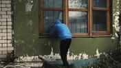Мужчина в капюшоне заглядывает в окно